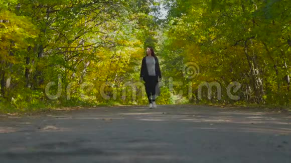 美丽的女孩走在秋天的公园里视频的预览图