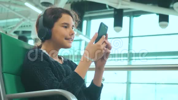 机场候机大厅供乘坐飞机的生活方式年轻快乐的少女戴着耳机听音乐视频的预览图