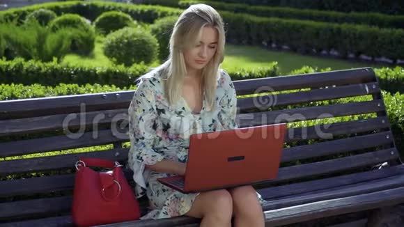 美丽的女孩坐在公园的长凳上视频的预览图