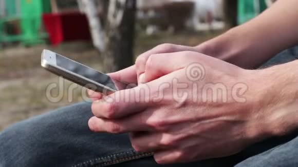 带着白色电话的年轻人坐在街上公园里户外视频的预览图