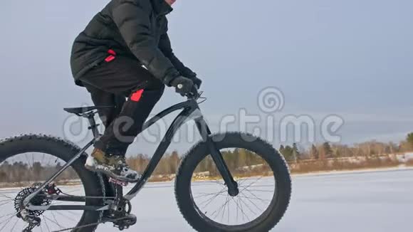 专业的极限运动员骑着一辆肥胖的自行车在户外骑自行车的人在冬天骑在雪冰上人类视频的预览图