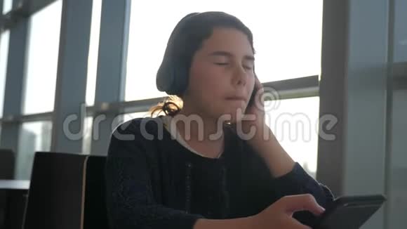 快乐的年轻少女戴耳机唱歌和听生活方式的音乐在智能手机上社会中的少女视频的预览图