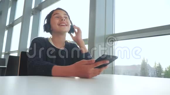 年轻快乐的十几岁女孩戴着耳机唱歌听着智能手机上的音乐社会生活方式中的少女视频的预览图