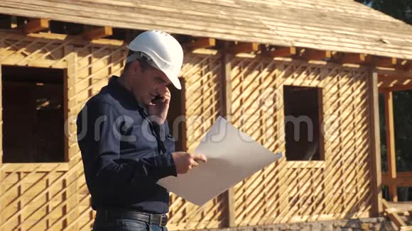 概念建筑构建建筑师慢动作视频戴着头盔的建筑工人站在一座建筑上手持一个视频的预览图