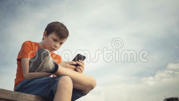 小男孩在他的智能手机上玩电子游戏视频的预览图