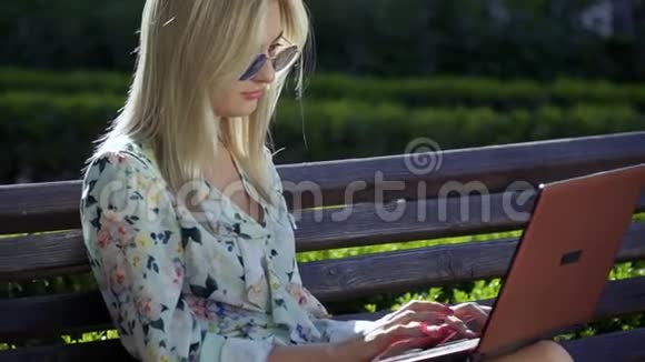 美丽的女孩坐在公园的长凳上视频的预览图