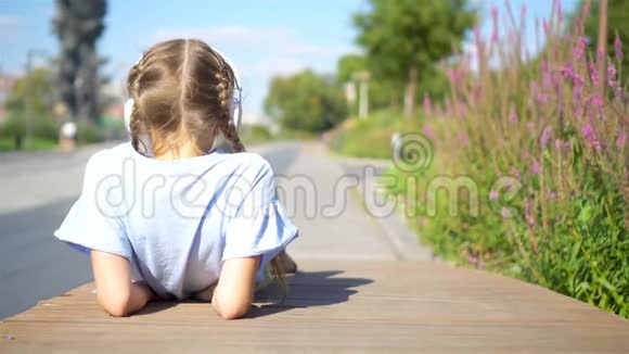 小可爱的女孩在公园里听音乐视频的预览图