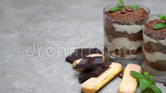 玻璃中的经典提拉米苏甜点和混凝土背景上的萨沃亚迪饼干视频的预览图