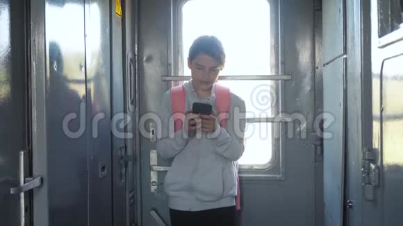 年轻的女孩旅行者带着背包的生活方式站在火车的窗户边有一部智能手机旅费视频的预览图