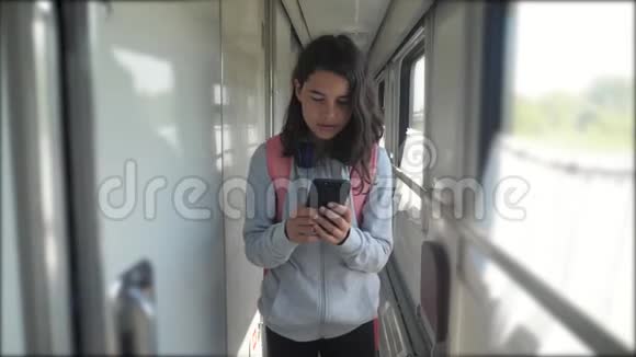 十几岁的女孩走在火车车厢里带着生活方式背包和智能手机旅游运输铁路视频的预览图