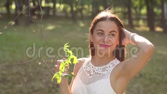 一个美丽的年轻女孩在阳光明媚的绿色公园穿着夏装的肖像视频的预览图