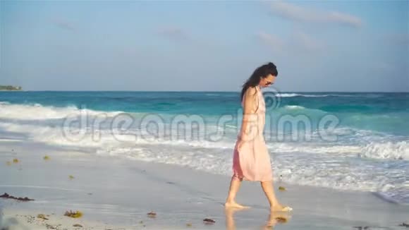 日落时穿着海边礼服的年轻美女视频的预览图