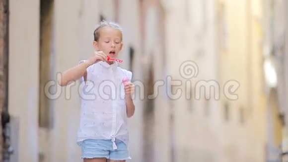 可爱的小女孩户外吹肥皂泡在欧洲城市白种人儿童享受暑假的肖像视频的预览图