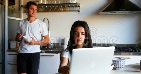 女人用笔记本电脑男人在厨房喝咖啡视频的预览图