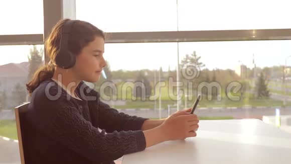 年轻快乐的少女戴着耳机听着音乐在智能手机上聊天交流生活方式视频的预览图