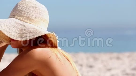 戴着草帽坐在沙滩上的女人视频的预览图