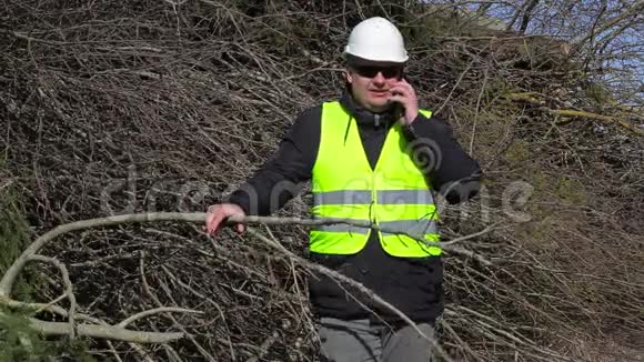 Lumberjack在一堆树枝附近用手机聊天视频的预览图