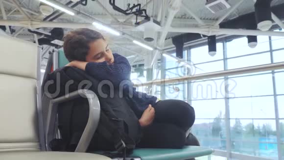 疲惫的少女少年旅行者睡在机场等待飞机起飞登机门的生活方式长凳和她所有的人视频的预览图