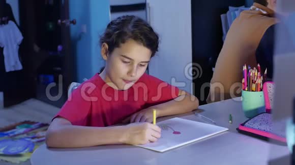 小女孩在桌子上画画女学生少年在室内用铅笔画画视频的预览图