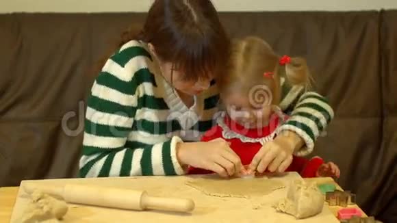 女人和蹒跚学步的女孩为家庭圣诞夜晚餐准备姜饼视频的预览图