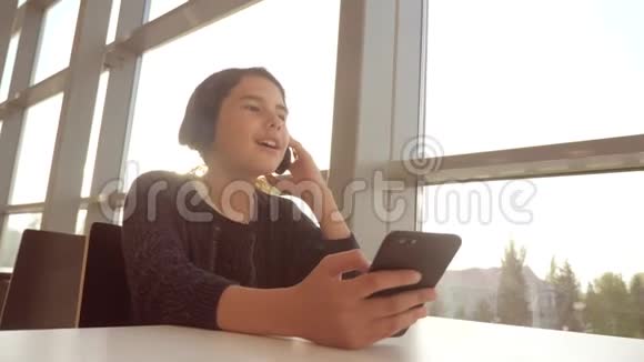 戴着耳机的年轻快乐少女在智能手机上唱歌和听音乐社交少女视频的预览图
