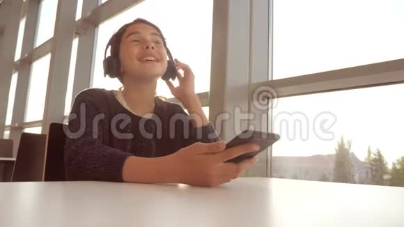 年轻快乐的十几岁女孩戴着耳机唱歌听着智能手机上的音乐生活方式社交中的少女视频的预览图