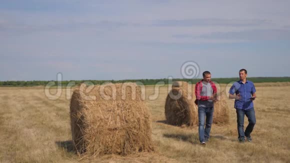 团队生活方式农业智慧农业理念两个男的农民工人走在田野的干草堆上视频的预览图