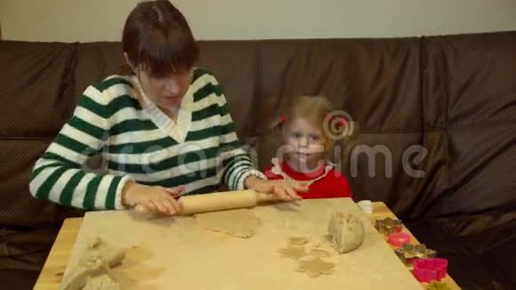 女人和蹒跚学步的女孩为家庭圣诞夜晚餐准备姜饼视频的预览图
