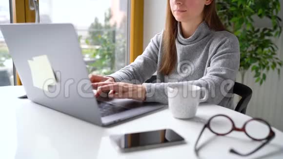 漂亮的女人坐在家里的办公室里用笔记本电脑工作视频的预览图