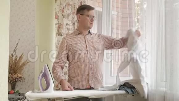 一个男人在他家的熨衣板上抚摸他的衬衫视频的预览图