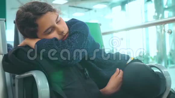 疲惫的少女少年旅行者睡在生活方式上机场等着飞机起飞登机口和她所有的人坐在长椅上视频的预览图