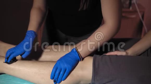 美容师从一个年轻女人的腿上取下头发糖膏视频的预览图