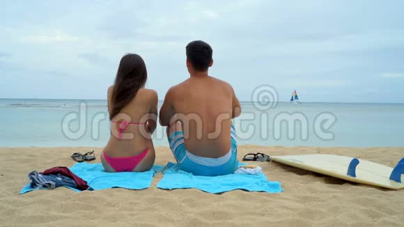 年轻夫妇坐在海滩上视频的预览图