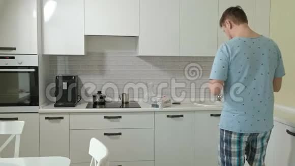 一个穿睡衣的男人在厨房里喝水上午视频的预览图