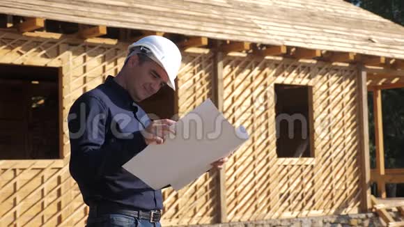 概念建筑构建建筑师慢动作视频戴着头盔的建筑工人站在一座建筑上手持一个视频的预览图
