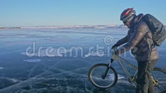 人在冰上骑着自行车走骑自行车的人穿着灰色的羽绒服背包和头盔冰的冰视频的预览图
