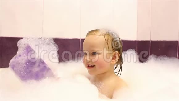 小快乐女孩在浴室里用泡沫洗澡他玩泡沫视频的预览图