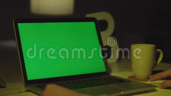 带有绿色屏幕的笔记本电脑黑暗的办公室完美地放置你自己的图像或视频视频的预览图