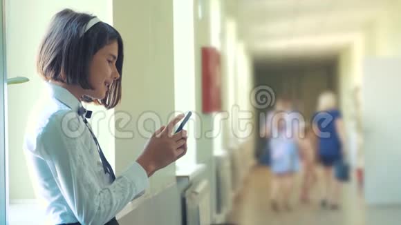 在学校概念上使用智能手机的女学生教育年轻的少女和使用生活方式智能手机站在旁边视频的预览图