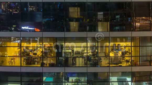 多层现代玻璃和金属办公楼中的发光窗在夜晚时光倒流时点亮视频的预览图