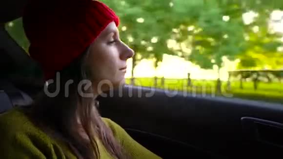 阳光明媚的一天幸福的年轻女子坐在副驾驶座上看着窗外视频的预览图