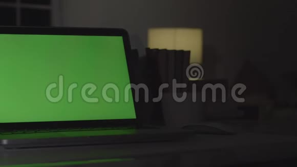 带有绿色屏幕的笔记本电脑黑暗的办公室完美地放置你自己的图像或视频视频的预览图