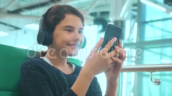 机场候机大厅供飞机飞行年轻快乐的少女戴着耳机听音乐视频的预览图