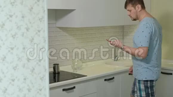 一个穿睡衣的男人在厨房里喝水上午视频的预览图