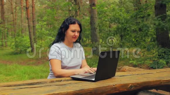公园里的年轻女子正在笔记本电脑上打字视频的预览图