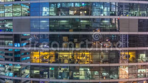 多层现代玻璃和金属办公楼中的发光窗在夜晚时光倒流时点亮视频的预览图