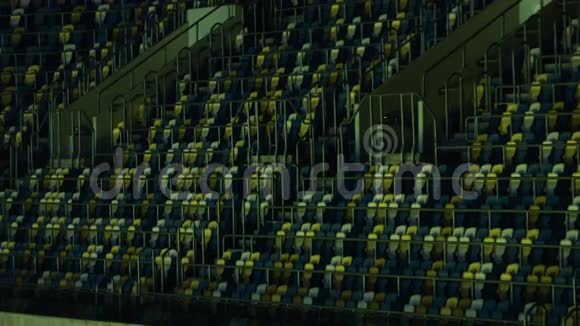 一个带扶手的体育场看台上的蓝色和黄色座位的图片视频的预览图