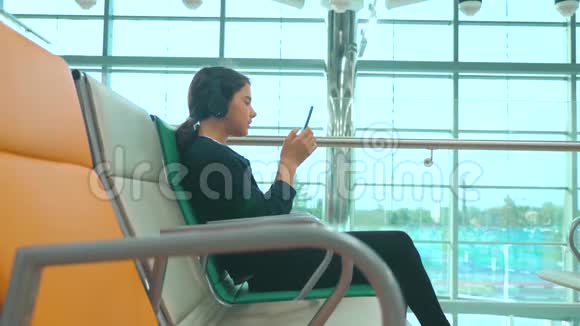 机场候机大厅供飞机飞行年轻快乐的少女戴耳机的生活方式听音乐视频的预览图