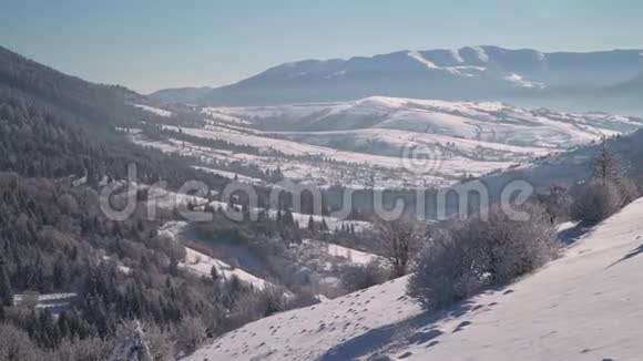 山里的冬天冬季森林山上白雪覆盖的树木蓝天视频的预览图