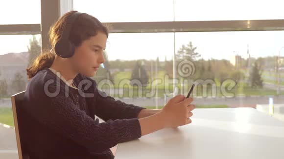 年轻快乐的少女戴着耳机听着音乐在智能手机上生活方式聊天在交流视频的预览图